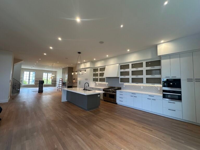 Spacious open-concept kitchen with white cabinets, kitchen island, and hardwood flooring.